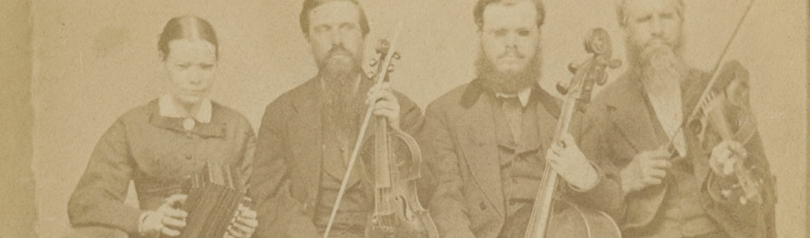 [Portrait of Hostetler family of blind musicians]. Mount Pleasant, Penna, [ca. 1866]. Picture shows one woman and three men, seated next to each other, and holding instruments. The woman holds an accordion in her lap and she looks slightly down. To her left is a man, his eyes closed, who holds a viola perpendicular to his lap with one hand and a bow in his other. To his left is a man resting a cello between his legs. He holds a bow across the base of the cello with his right hand. To his left is the last man, his eyes closed, who holds a violin by his left shoulder and a raised bow in in his right hand. The woman, as well as the man who holds a cello, wear glasses. The woman wears a dark-colored corseted dress with long sleeves and a long skirt. The men, who look toward the viewer, are bearded and wear dark-colored suits. [End of description]