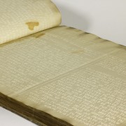 Picture shows an open volume of an 1838 edition of “The Students' Magazine: Published Monthly, at the Pennsylvania Institution for the Instruction of the Blind.” The text is printed in raised-letter line type. The volume is open to an oblique view of a title page. Letters are in capitals and the text is not easily legible given the angle of the view. Part of the header is legible and reads: "STUDENTS’ MAG." Part of the opposite page with embossed type is visible. [End of description]