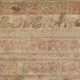 Picture shows the upper edge of a writing board or tablet over a white background. The tablet is made of a brown cardboard-like material with a faded pink and blue marbled pattern and has raised, tactile, evenly spaced bars on its surface. In the center of the first bar, handwritten script reads “Mrs. E. A. Lusk.” [End of description]