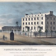 Picture shows a four-story rectangular building with many rectangular windows. The building includes two front entrances with porticos. The structure is white, and its front is lit by sunlight. Pedestrians – eight total with six men, two women and one boy – walk on the sidewalk in front of and across from the building. Small trees evenly line the sidewalk in front and to the left of the building. A dark-colored watchman’s guardhouse, shaped like a chimney, stands across the street from the building. A man with a cane, and a boy, holding his hand, walk past the guardhouse. The boy appears to be gesturing in the direction of the guardhouse and the building. Text printed below the images reads: “Lith. Of J. T. Bowen, Phila. Pennsylvania Institution for the Instruction of the Blind. Published by J.T. Bowen at his Lithographic & Print Colouring Establishment, 94, Walnut St Philada. Entered according to act of Congress in the year 1840 by J. T. Bowen in the Clerk’s Office of the Dt. Ct. for the En. Dt. of Pa.[End of description]